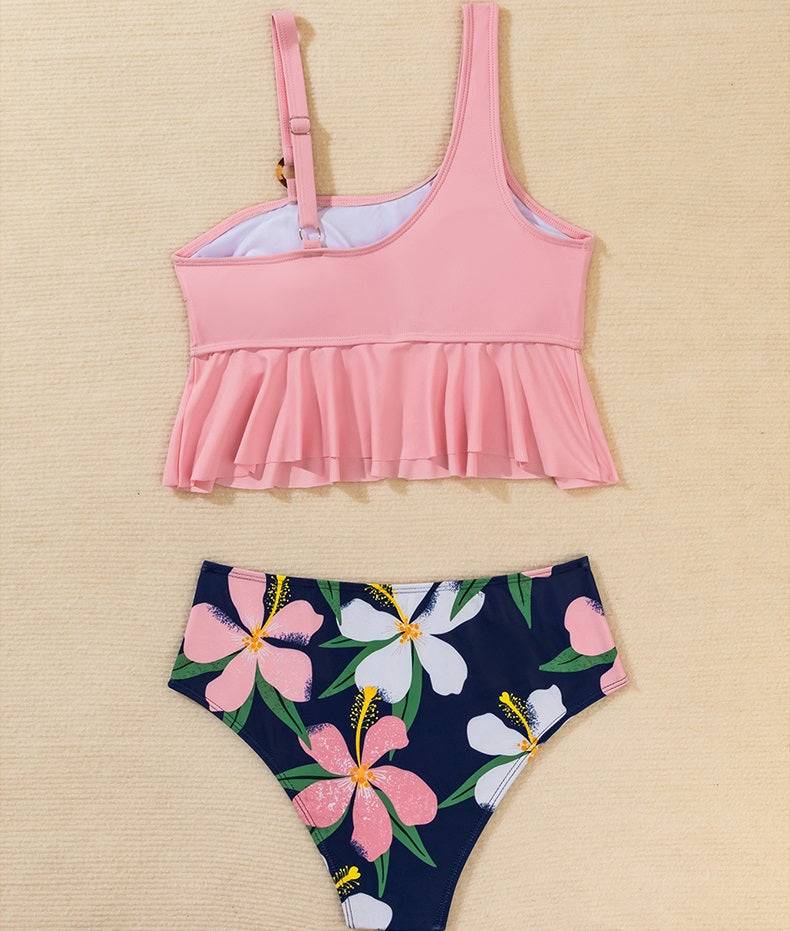 Розов бански от две части ''Crystal'' с флорално долнище, изложен върху бежова повърхност.