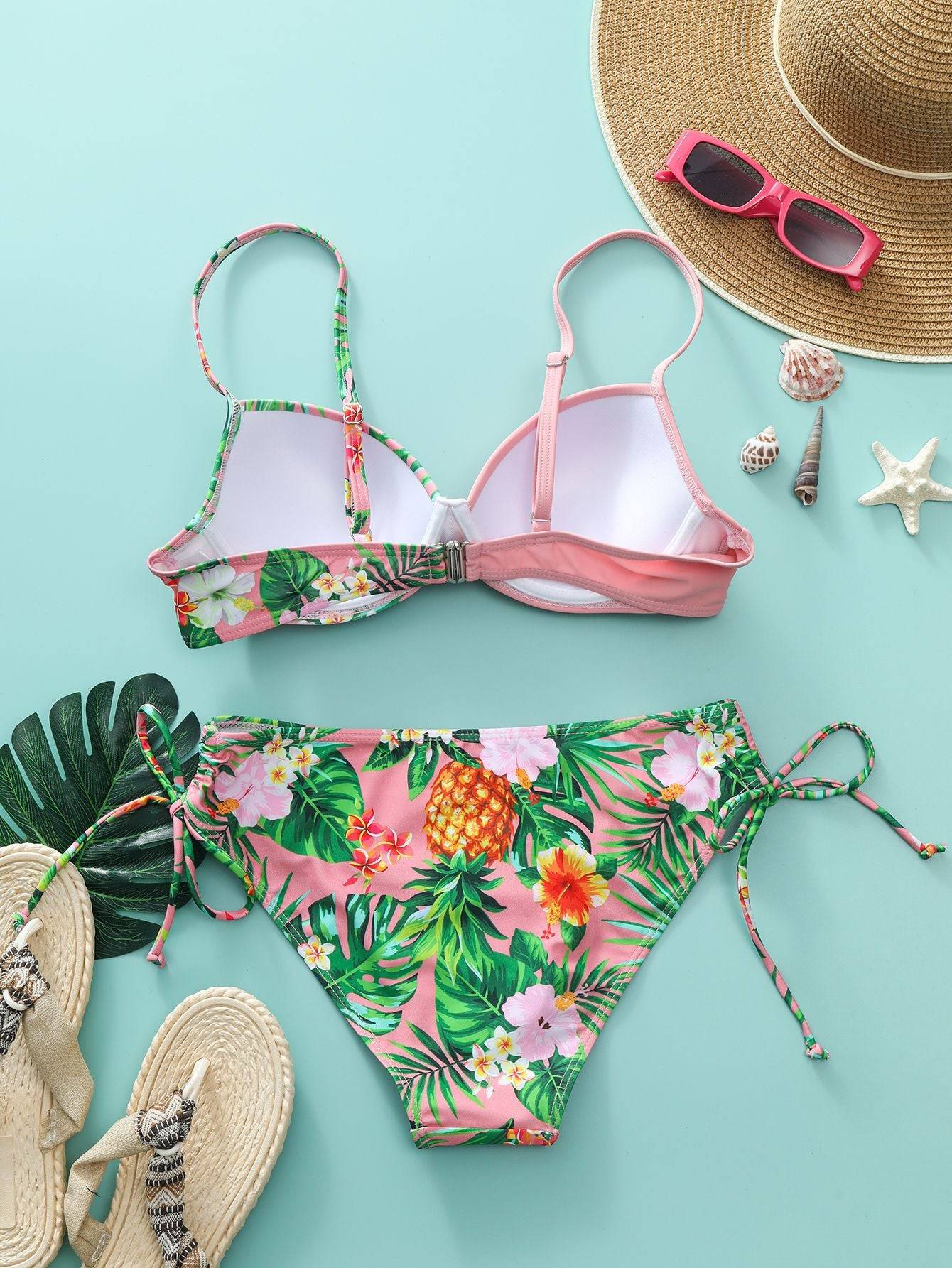 Гръб на бански ''Reflection'' в розово с флорални мотиви, показан с плажни аксесоари. Регулируеми презрамки и удобна закопчалка за перфектно прилягане.